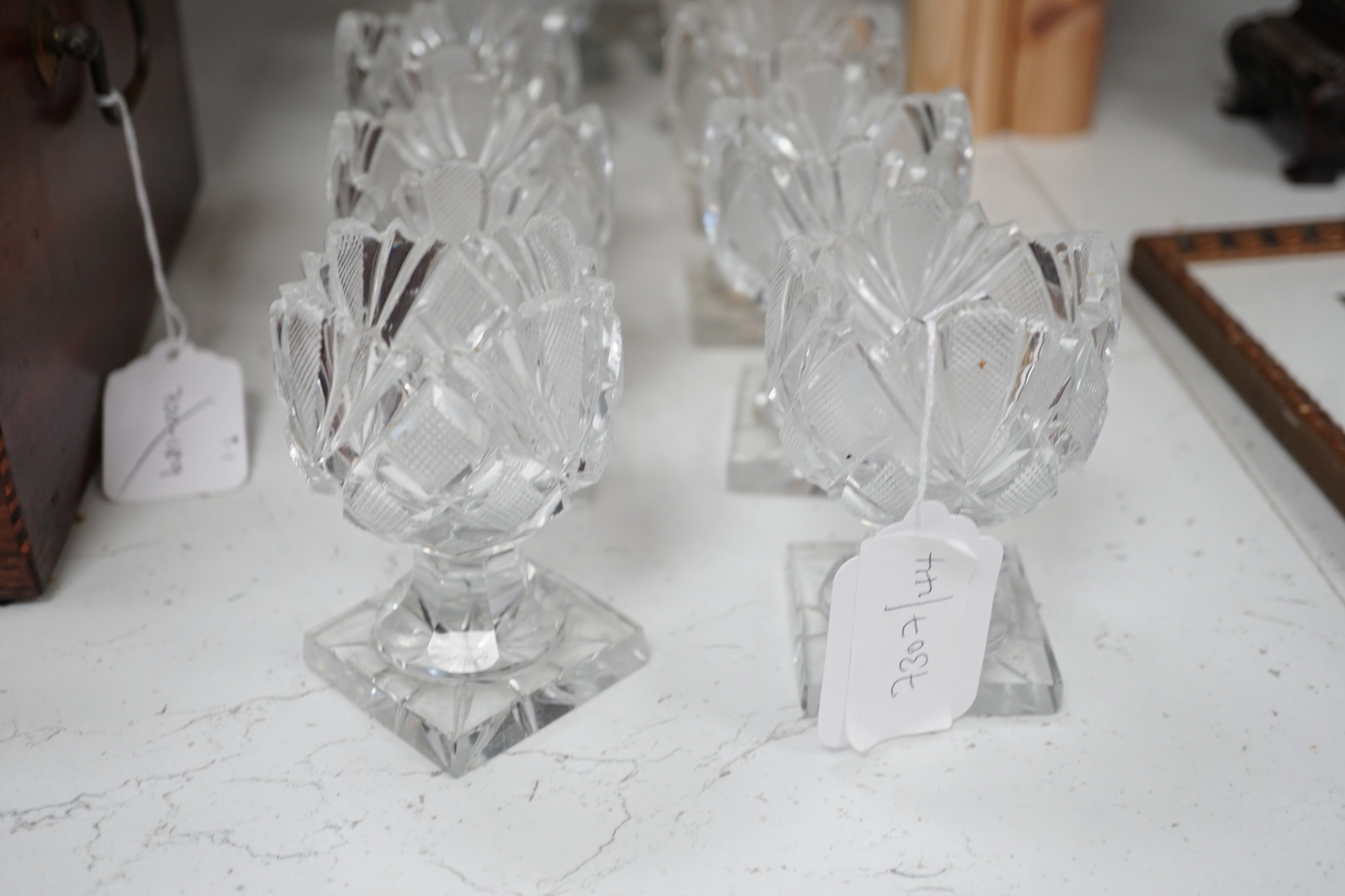 A set of twelve Victorian square base cut glass salts and four other 19th century clear glass salts.